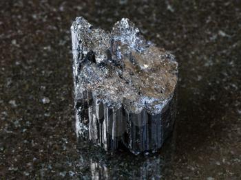 macro shooting of natural rock specimen - raw crystal of black Tourmaline (Schorl) stone on dark granite background
