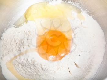 cooking of pie - flour with broken egg close up in steel bowl
