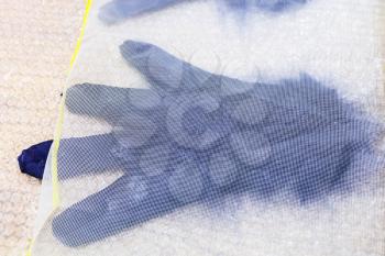 workshop of hand making a fleece gloves from blue Merino sheep wool using wet felting process - wet glove with new fibers under plastic mesh
