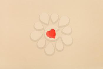 one little heart cut out of red paper on background from yellow navajo white pastel paper