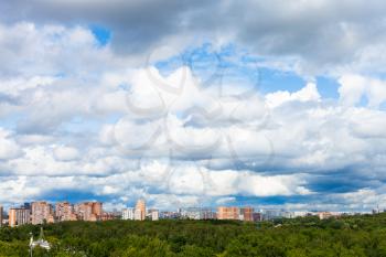 low dense white clouds in blue sky over city on sunny summer day