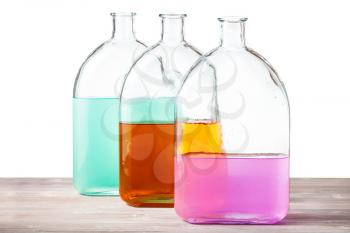glass flasks with color watercolour solutions on wooden board with cutout background