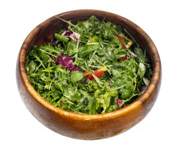 oiled green salad from fresh greens and vegetables in wooden bowl isolated on white background