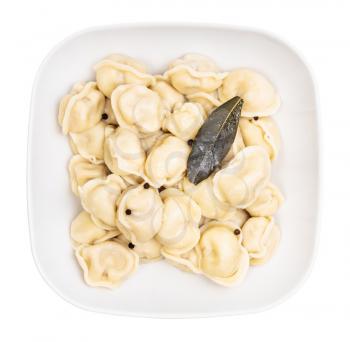 top view of boiled Pelmeni (russian dumplings filled with minced meat) with peppercorns and bay leaf in gray bowl isolated on white background