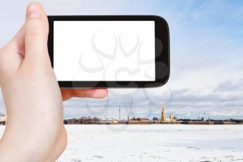 travel concept - tourist photographs of frozen Neva river and Peter and Paul Fortress in Saint Petersburg city in March on smartphone with empty cutout screen with blank place for advertising