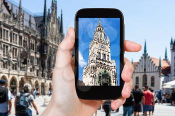 travel concept - tourist photographs of tower of New City Hall (Neues Rathaus) on Marienplatz in Munich city on smartphone