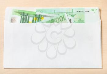 several one hundred euro notes in open mail envelope on wooden table