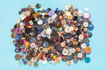 top view of heap of many various buttons on blue background