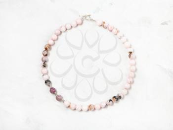 hand crafted necklace from cherry blossom rose quartz beads on gray concrete surface
