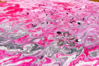 surface of abstract painting with flowing pink and silver acrylic paints decorated by bugles