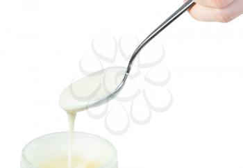 natural organic white honey pouring from steel spoon in glass jar isolated on white background