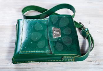 handcrafted green leather tablet bag on gray wooden table