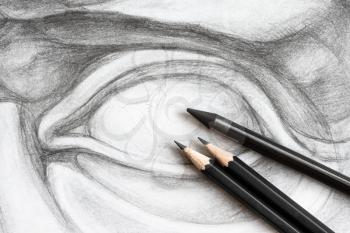three graphite pencils on hand-drawn academic drawing of David's eye close up