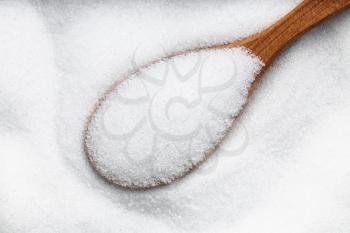 top view of wood spoon with sugar substitute - crystalline extract of stevia plant close up on pile