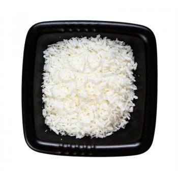 top view of coconut flakes in black bowl isolated on white background