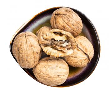 top view of shelled and whole walnuts in ceramic bowl isolated on white background