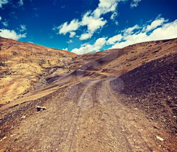 Vintage retro effect filtered hipster style travel image of dirt road in mountains Himalayas. Spiti Valley,  Himachal Pradesh, India