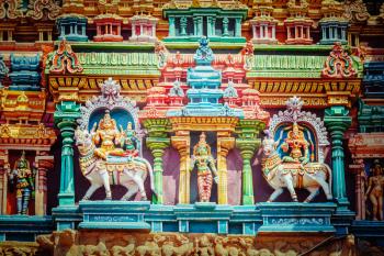 Vintage retro hipster style travel image of Shiva and Parvati on bull images. Sculptures on Hindu temple gopura tower. Minakshi Temple, Madurai, Tamil Nadu, India