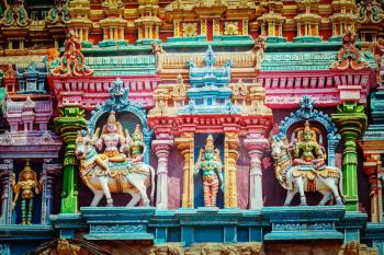 Vintage retro hipster style travel image of Shiva and Parvati on bull images. Sculptures on Hindu temple gopura tower. Meenakshi Temple, Madurai, Tamil Nadu, India