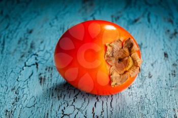 Fresh ripe persimmon on a blue wooden background