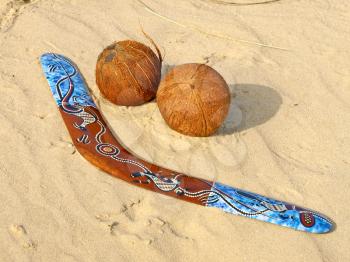 Colorful boomerang and coconuts on a sand.