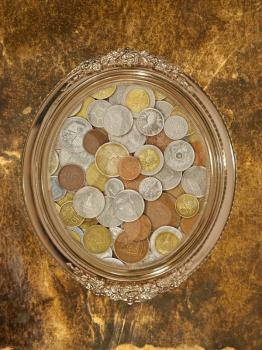 Golden oval photo frame with numismatic coins collection inside on grungy wall.