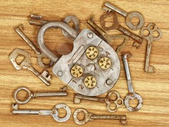 Old metal lock and keys on a wooden table background.