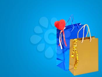 Valentines Day holiday gift bags with red heart on blue background with empty space.