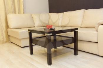 Comfortable white corner leather sofa and wooden coffee table.