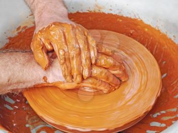 Potter hands taken closeup on pottery wheel.Pop view.