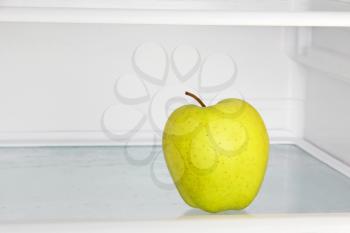 Lifestyle concept.Yellow apple in domestic refrigerator taken closeup.