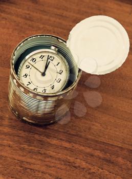 Canned time concept.Time preserved in tin can on wooden table taken closeup.