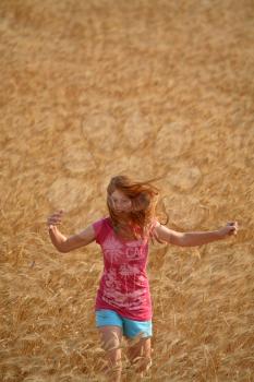 Redhead girl running through a Saskatchewan wheat field