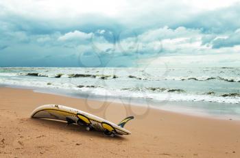 Board for windsurfing on the beach and cloudy sky