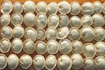 Frozen meat dumplings on the kitchen board. Dumplings or ravioli is a traditional East Slavic kitchen dish also known as pelmeni