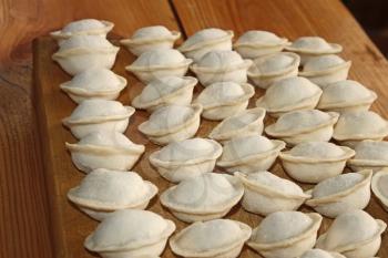 Frozen dumplings with meat on the kitchen board. Dumplings or ravioli is a traditional East Slavic kitchen dish also known as pelmeni
