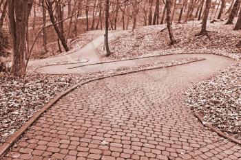 Park paved walkway that runs steeply down, early spring evening in Lviv, Ukraine, toned photo