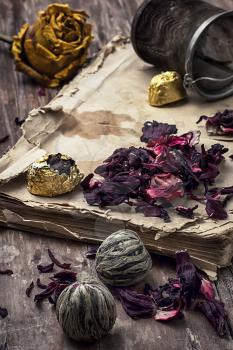 old book is strewn with the tea leaves on wooden background,tinted in vintage style