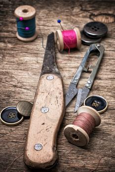 old knife and sewing supplies on old wooden background
