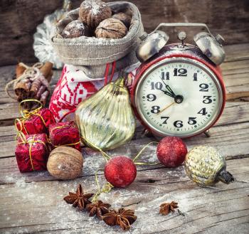 An alarm clock and bag of nuts on the background of Christmas decorations