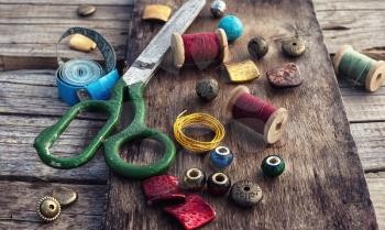 outdated tools and jewelry for needlework on wooden background