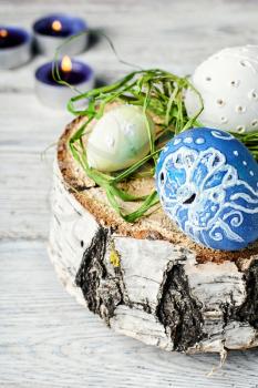Decorated with painted Easter eggs on birch slice on light background