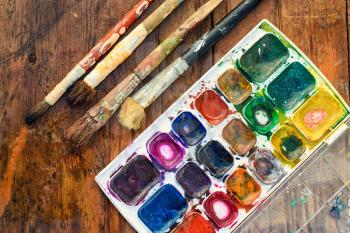 Set of watercolors and different brushes for painting on wood vintage palette