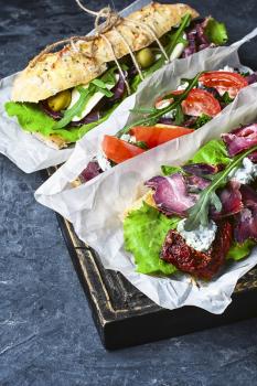 sandwiches with bacon and vegetables on blue slate background
