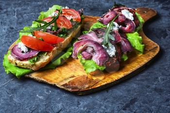 sandwiches with bacon and vegetables on blue slate background