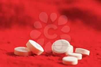 White pills on red blurred background. Medicament tablets template