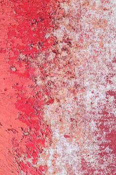 Old wall in color peeling red pink paint. Cracked exterior texture background