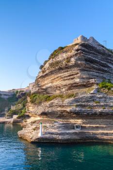 Rocky cliff with white lighthouse lantern in the entrance of Bonifacio port, South part of Corsica island, France