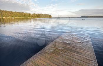 Old wooden pier goes under deep water on the lake