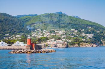 Red lighthouse tower on stone breakwater. Ischia Porto. Mediterranean sea, bay of Naples, Italy